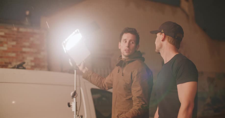 Two men turn on a light under the light rain on the street of a small town at night