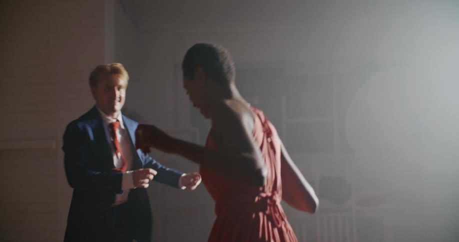 A man and woman dance together in a dimly lit room