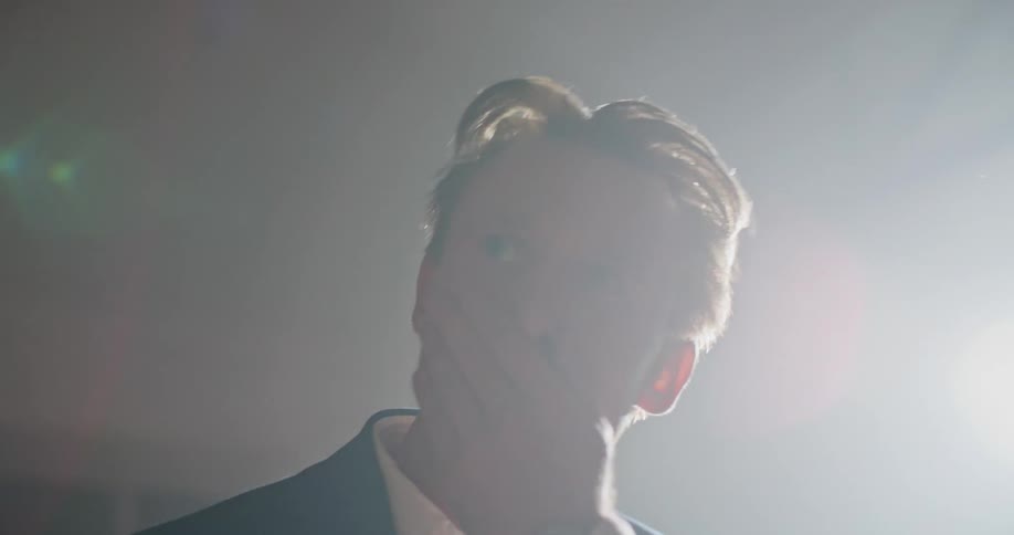 A man nervously wipes his mouth while standing and greeting someone with a handshake