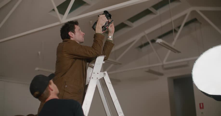 A man is taking photographs on a ladder