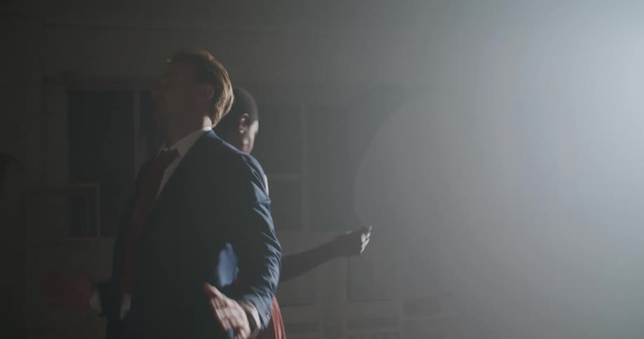 A man holds a camera and gets ready to photograph a man and woman dancing together