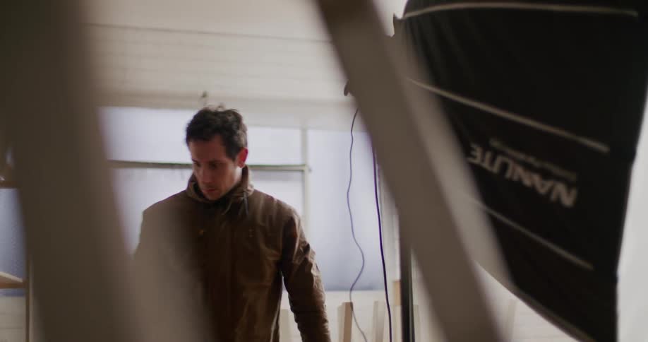 A man assembles a large photography light and another man walks around to look at the front of it