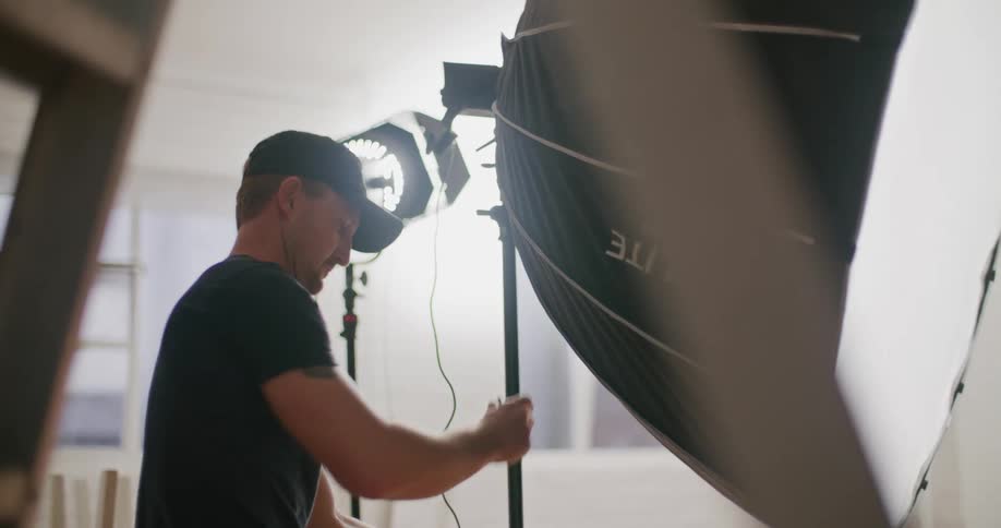 A man shifts a large umbrella light at a photo shoot