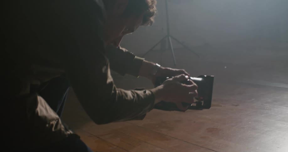 Photographer kneeling on the floor of a dimly lit room taking pictures