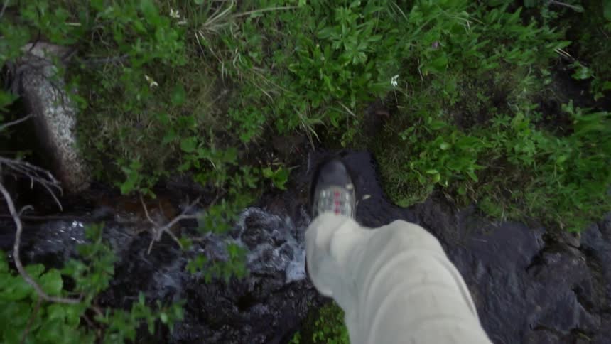 A person walks over a small brook