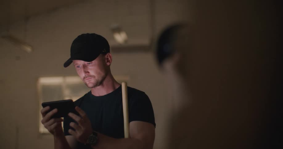 Filmmaker filming a man checking his phone ona dimly lit room