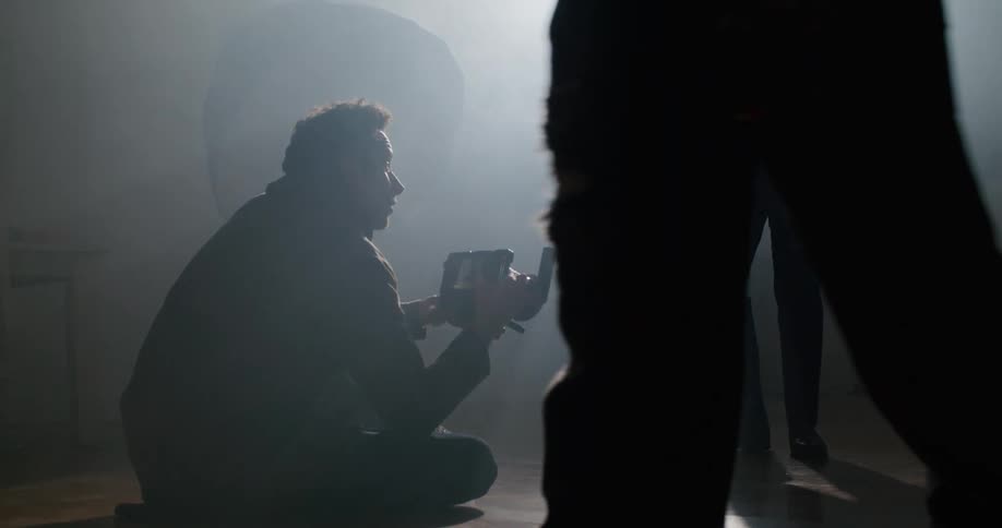 A man is sitting and filming two people dancing
