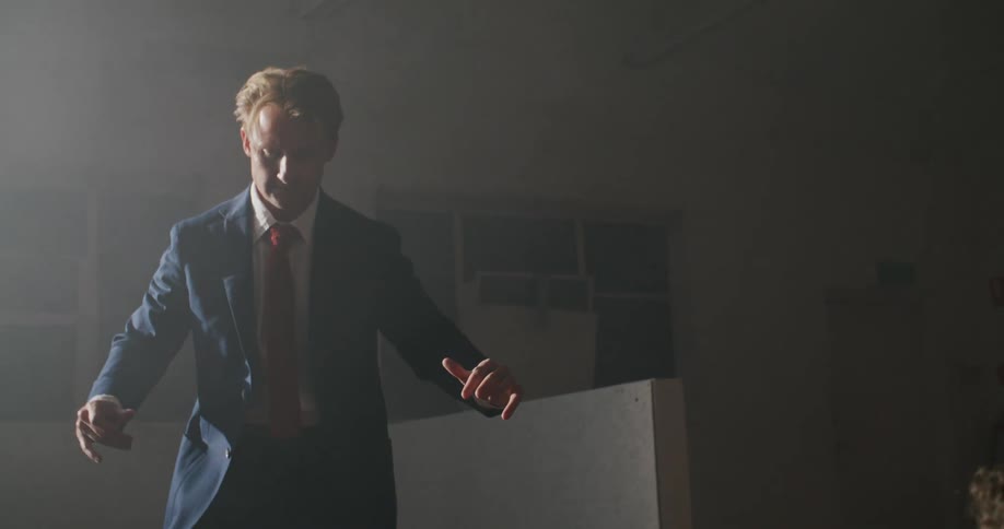 A man in a suit poses and slightly dances in front of a male photographer