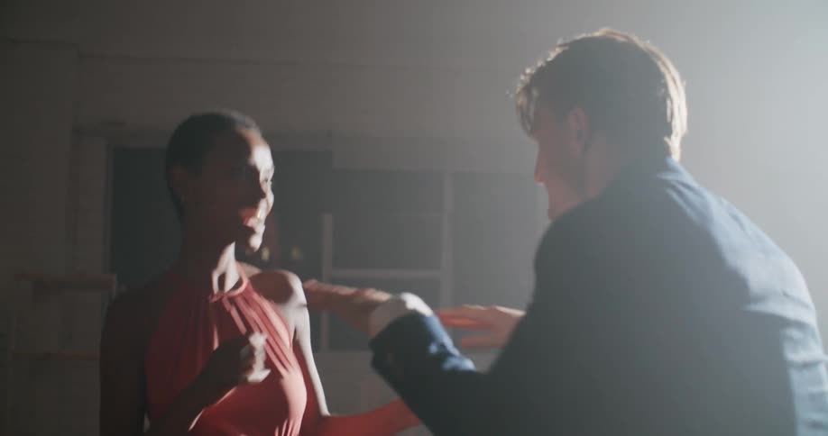 A man and a younger woman dance together in a dimly lit room