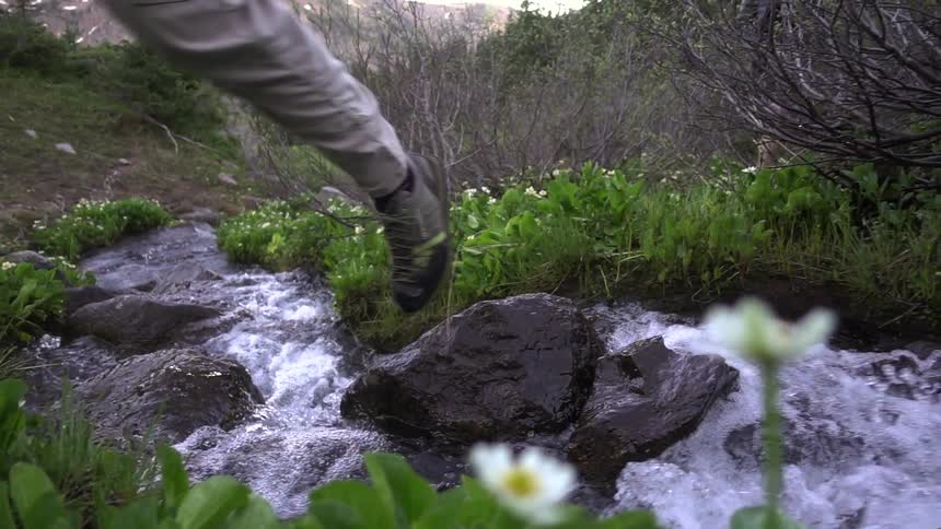 A person walks over a rushing stream