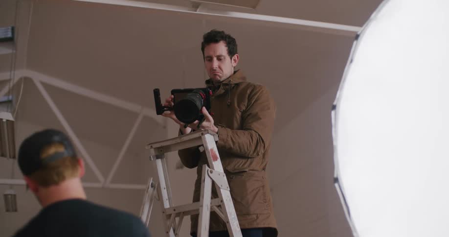 A photographer stands on a ladder during a photoshoot
