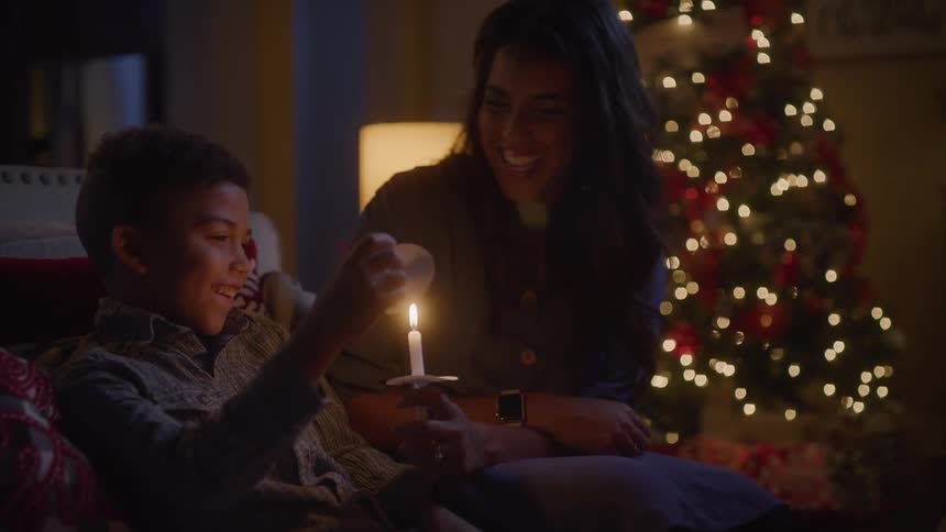 A woman and a boy are playing a candle in a living room