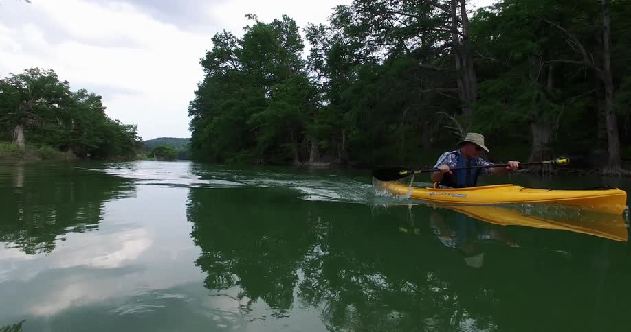 A kayaker wades through a narrow river