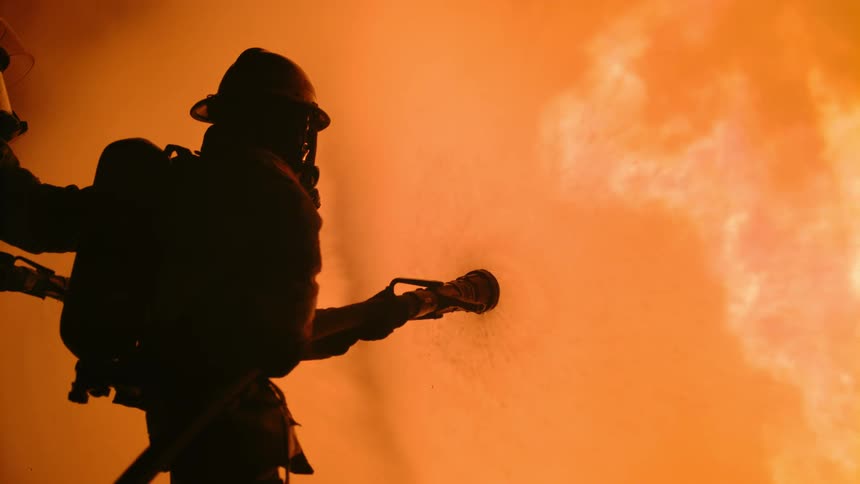 Firefighters dousing a raging fire with water at night