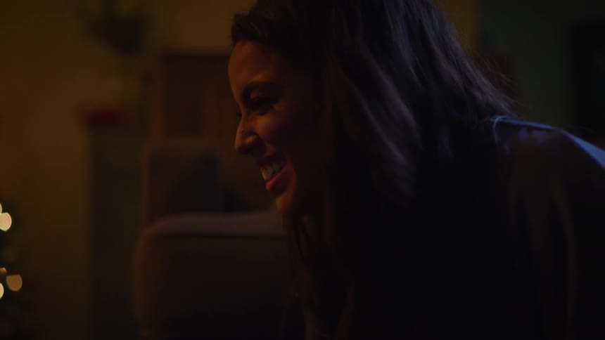 A woman sits by the christmas tree at home and talks and laughs