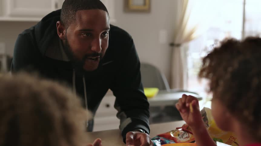 A man talks with his children as they eat