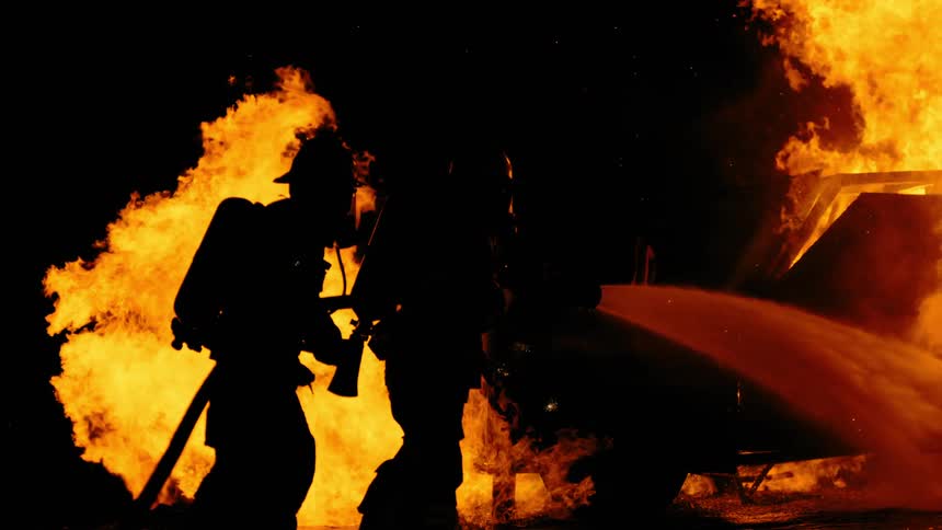 Two firefighters are trying to extinguish a fire with water hose