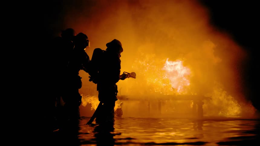 Firefighters dousing a raging fire with water at night