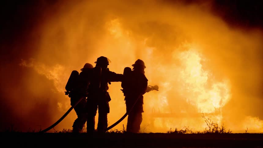Three firefighters fight a structure fire in the dark