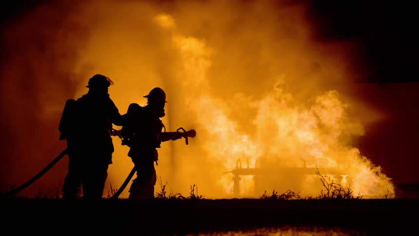 Silhouettes of firefighters battling huge flames