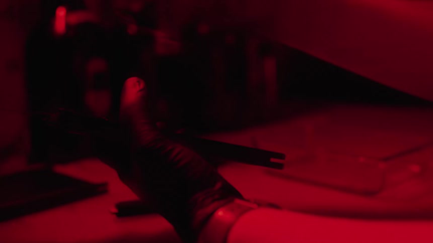 Person wearing black latex gloves develops photographs inside a dark room