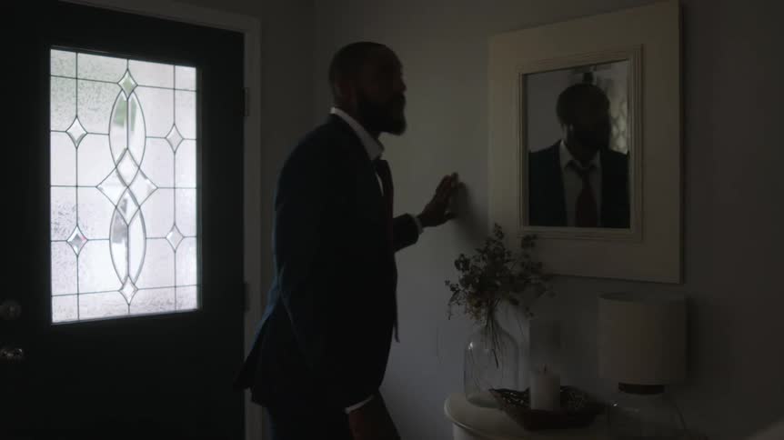 Man in suit and with a beard looks in the mirror