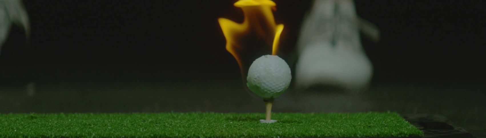 A person drives a golf ball that is on fire