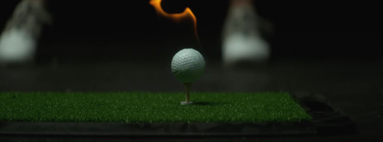 A golf ball on fire flies away after being hit by a club