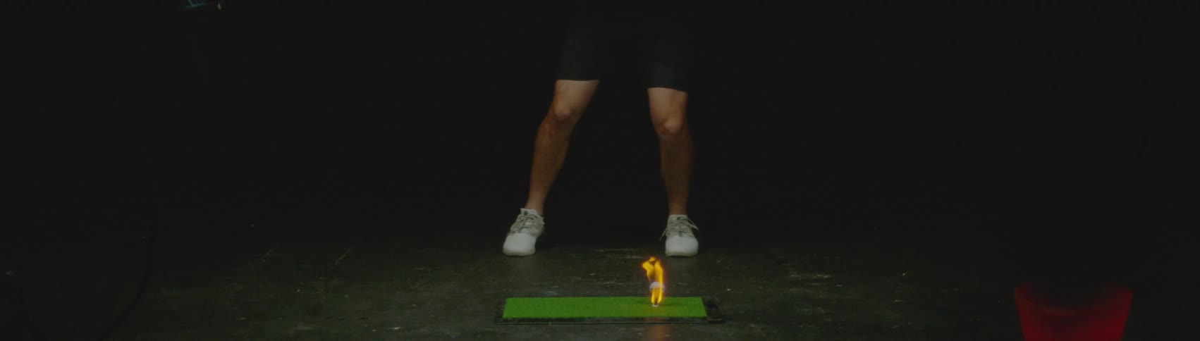 Golfer hitting a golf ball on fire over a small green tee