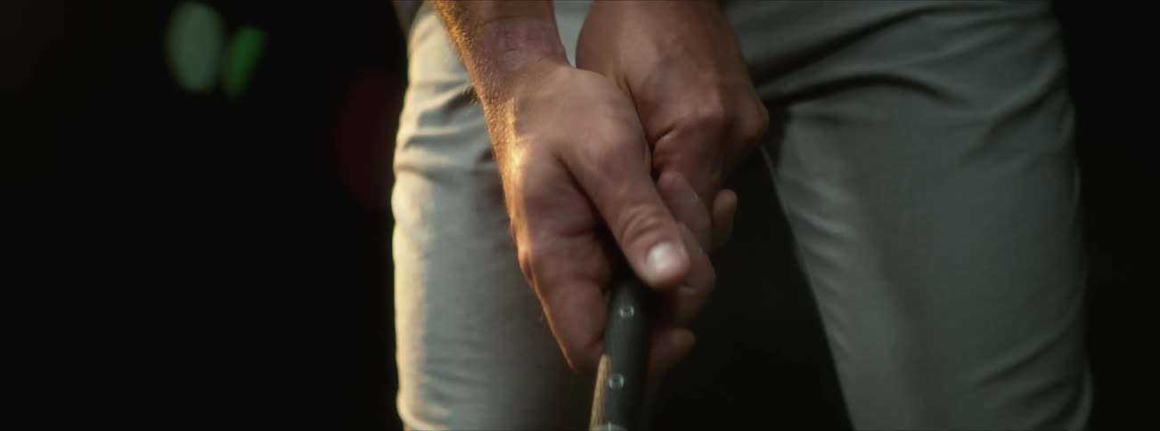 Man grips handle of golf club preparing for a swing