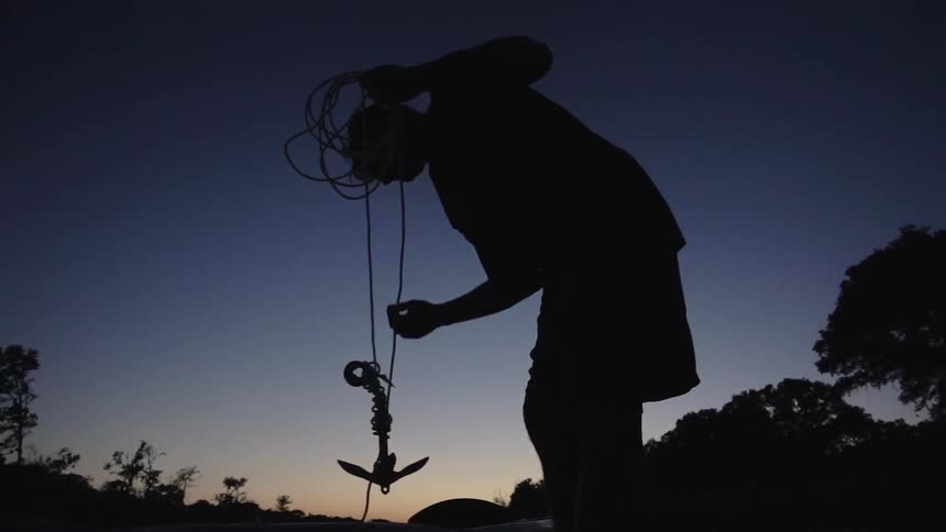A man is lifting an anchor at sunset