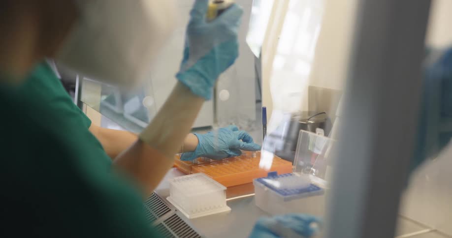 An employee in a medical lab fills test tubes with a long syringe