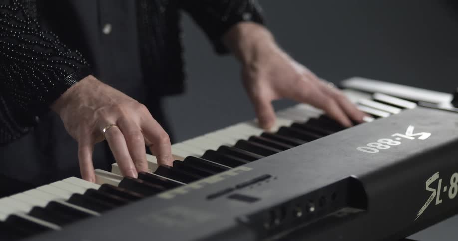 Man dressed in black playing a synthesizer inside a room