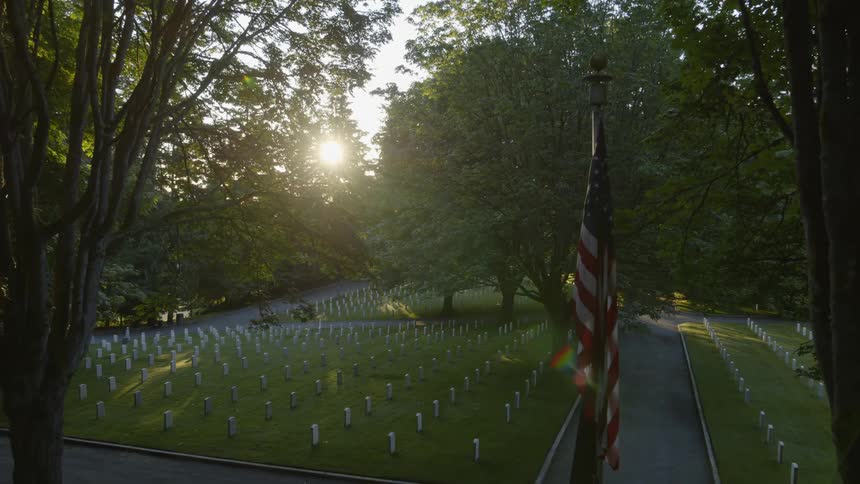 Pullback reveal of the American Flag standing watch over veteran gravesites