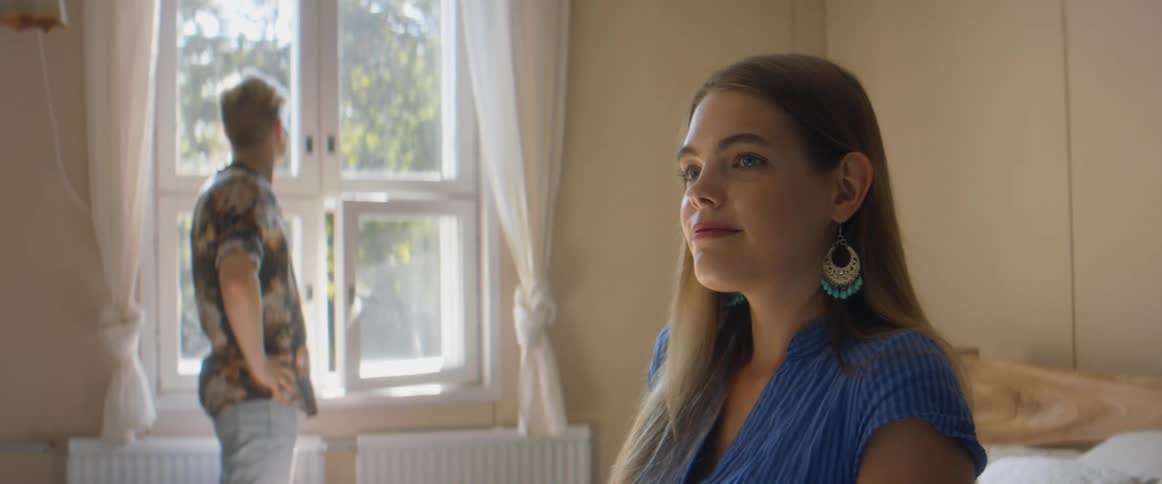A woman and a man in a room with a wall and window in the background