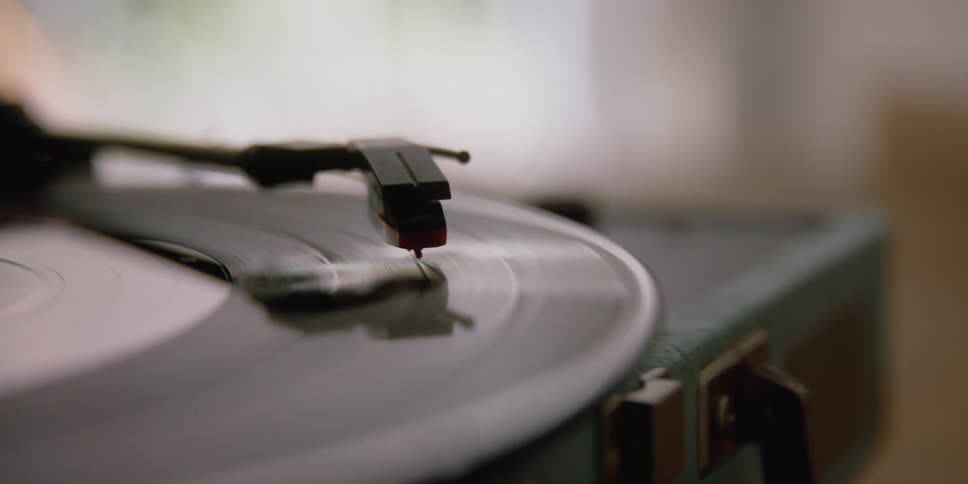 A record player with a needle with a record spinning in a room