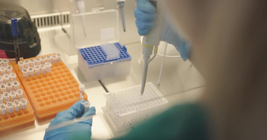 A nurse in a laboratory with gloves and a mask working with test tubes