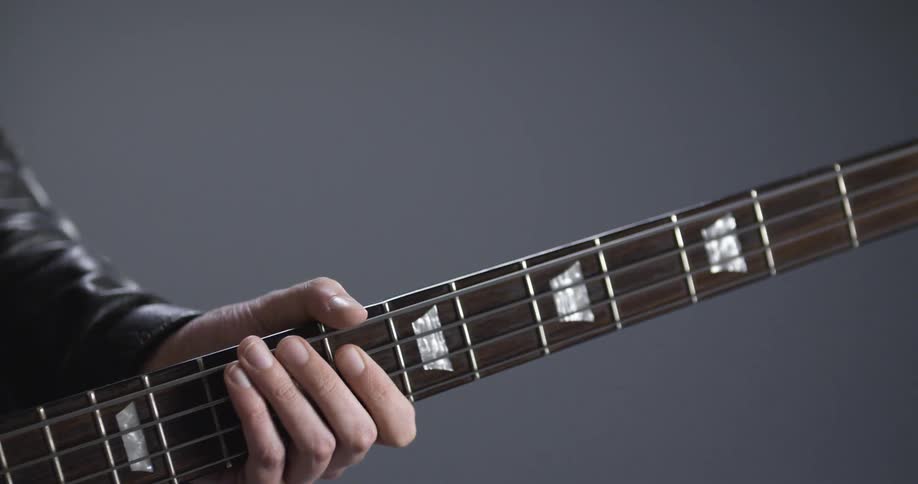 Musician places hand over the mast of a bass while strumming