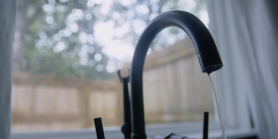 Water pouring from the faucet over the kitchen sink at home