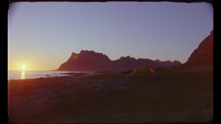 Sun setting over a lake next to mountains under a clear sky