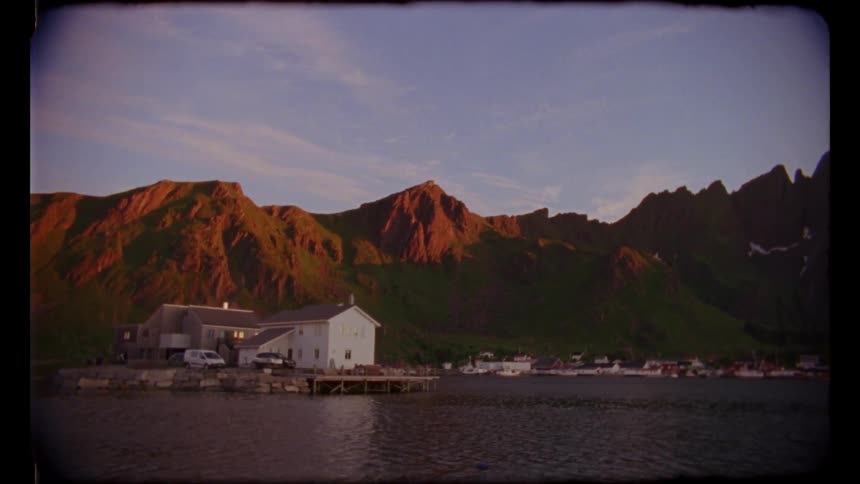A house near a lake with a mountain range sky and clouds in the background