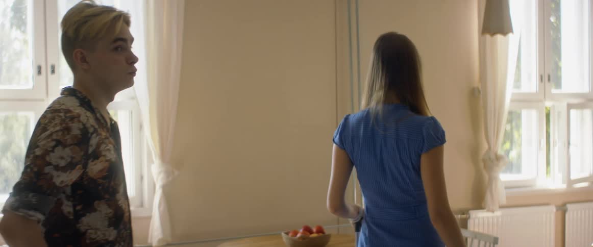 A woman and man pull luggage behind them as they examine a room in a house