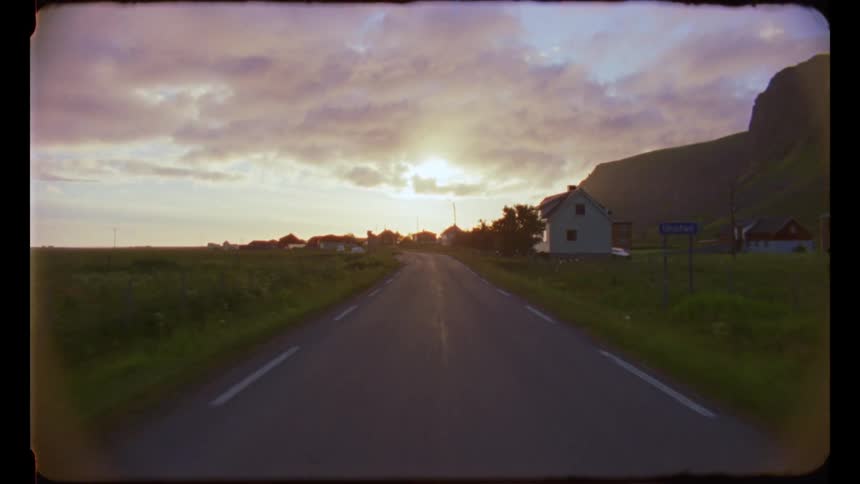Highway flows past houses set near mountain under cloudy sky