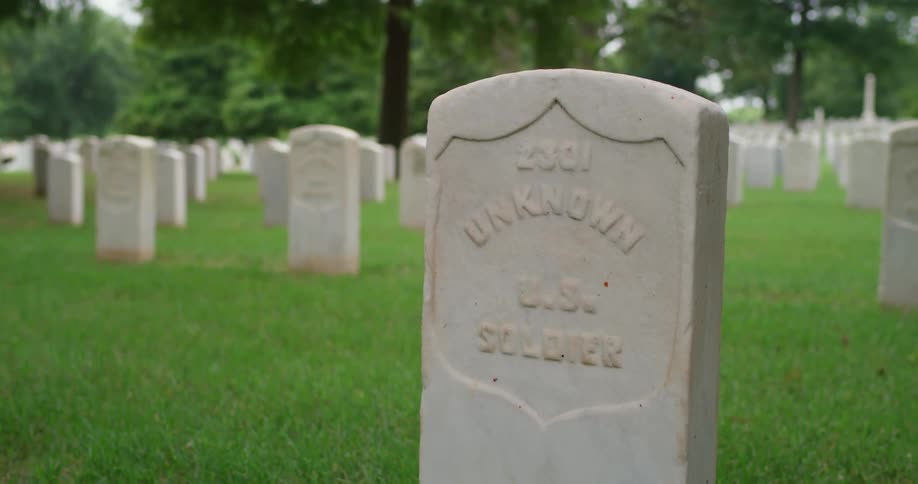 A look at a tombstone inside a graveyard with multiple gravestones visible at a distance