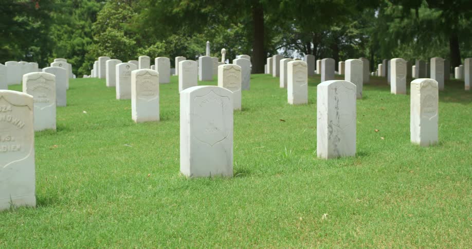 The graveyard is lined with white tombstones on a sunny day