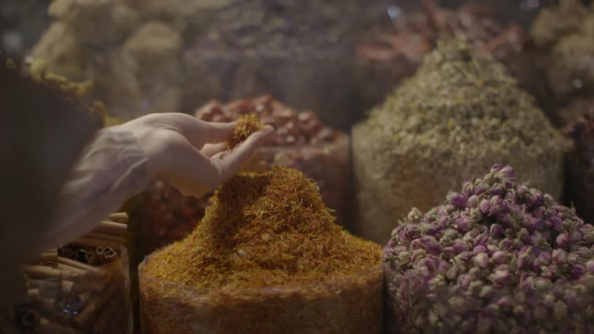 A woman bends to smell the aroma of the fresh spices and herbs in a market