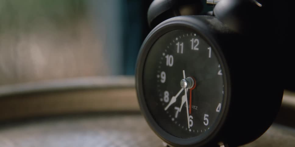 Black vintage alarm clock sitting on a table inside a room
