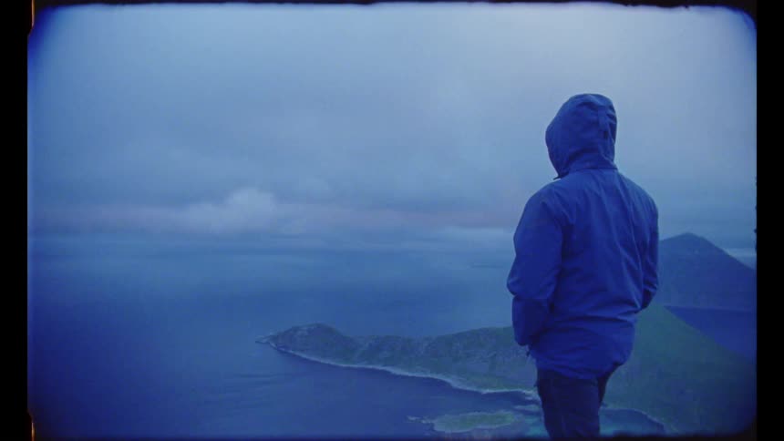 A person that is standing outside on a cliff looking into the distance