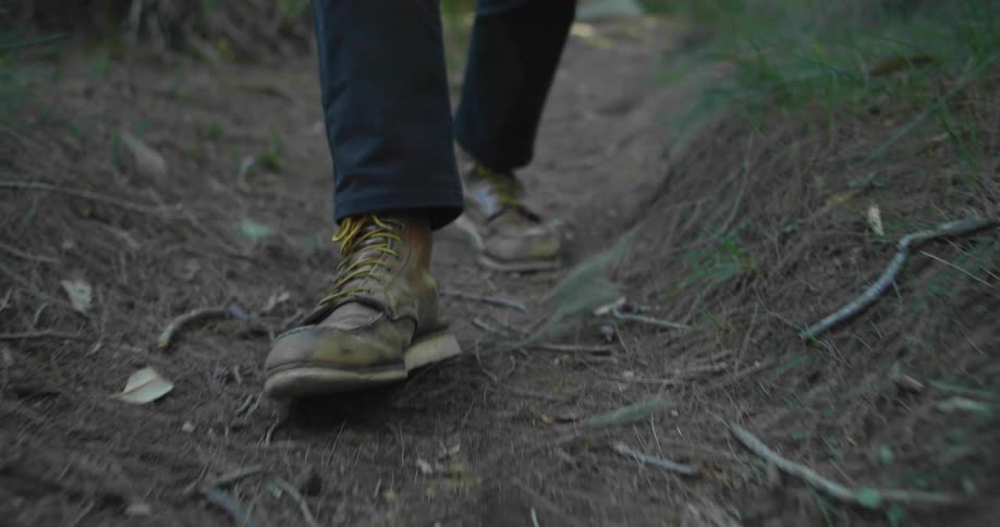 A man is walking in the wilderness as his shoes are in focus