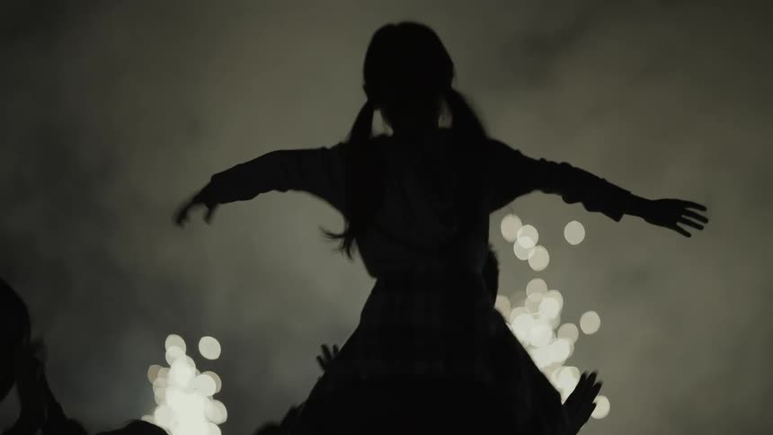 A silhouette of people dancing with fireworks and smoke in the background